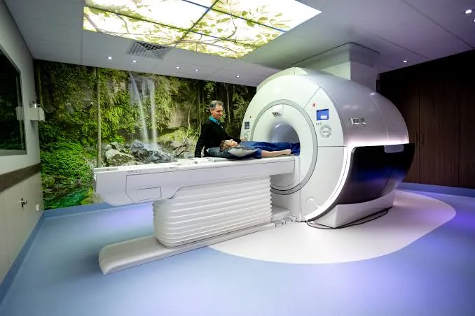 Patient installé sur la table d'IRM avant l'examen, dans une salle apaisante, accompagné d'un membre de l'équipe soignante